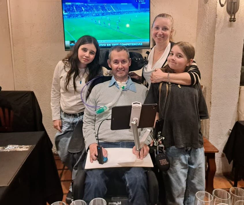Una persona usuaria de silla de ruedas acompañada por tres familiares durante la cena de fundación.